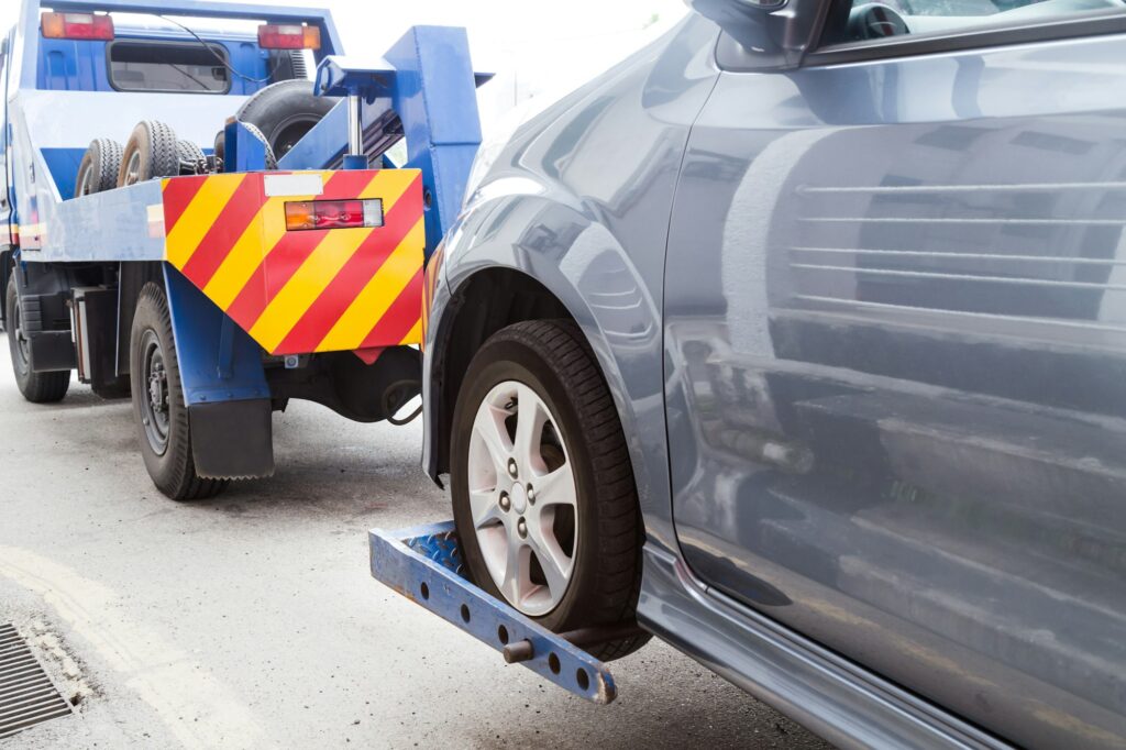 Tow truck towing a broken down car on the street
